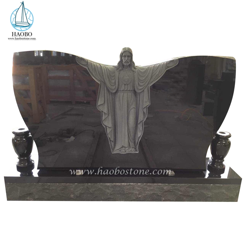 黒御影石の蝶の形をしたイエスの彫刻が施された葬式の墓石
