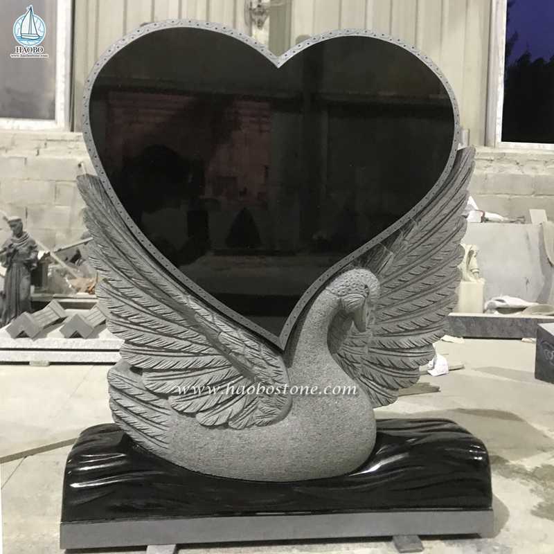 黒御影石のハート型の白鳥の彫刻が施された葬儀の墓石
