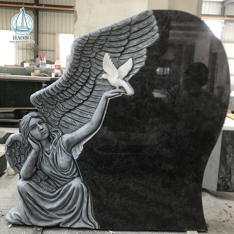 鳩が彫られた葬儀の墓石を持つ黒御影石の天使
